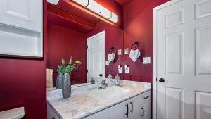 een rode badkamer met een wastafel en een vaas met bloemen bij Knockan Hill Rentals - Ground Floor Suite in Victoria