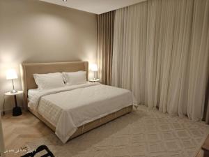 a bedroom with a bed with white sheets and two lamps at اتزان in Quai