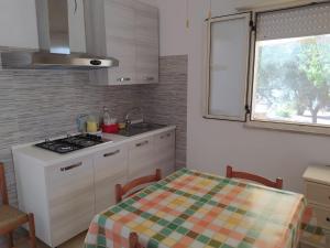 a kitchen with a stove and a table and a window at Villetta a 100 MT dal mare via Nepole Torre Vado in Morciano di Leuca