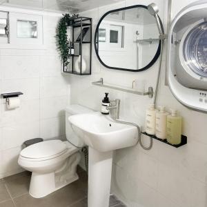 a bathroom with a toilet and a sink and a mirror at Adam stay in Suyŏng