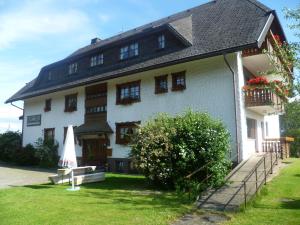 une grande maison blanche avec un parasol dans la cour dans l'établissement Hotel Gasthof Straub, à Lenzkirch