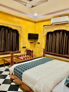 a bedroom with a bed and a tv on the wall at Hotel Queen Royal Jaisalmer in Jaisalmer