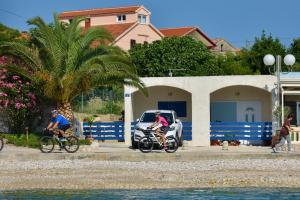 zwei Personen Fahrrad fahren und ein Auto am Strand in der Unterkunft Apartment Rita in Preko