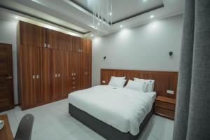 a bedroom with a large white bed and wooden cabinets at Ultra Aparthotel in Tete