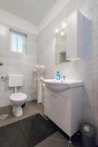 a white bathroom with a toilet and a sink at Apartment Rita in Preko +17 photos