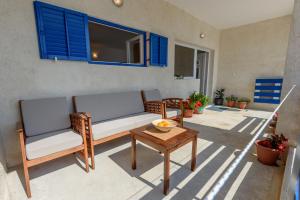 eine Terrasse mit 2 Stühlen, einem Tisch und blauen Fenstern in der Unterkunft Apartment Rita in Preko