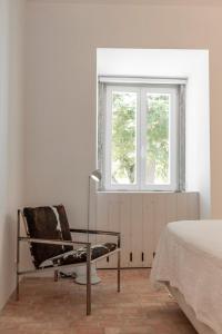 a bedroom with a chair and a window at Dona Ana House in Tavira