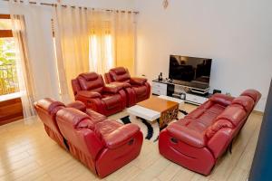 a living room with red leather chairs and a flat screen tv at Casa tranquila in Kigali