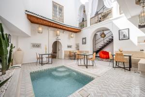 an indoor pool in the middle of a room with tables and chairs at Riad LILIA in Marrakech