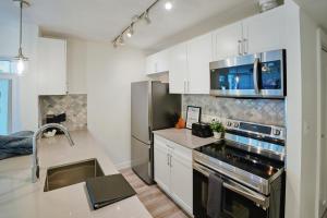a kitchen with white cabinets and a stainless steel appliances at Cozy Urban Living! 2 mins from BC place, private parking ! in Vancouver