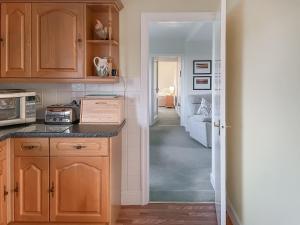 a kitchen with wooden cabinets and a hallway at Thelma's House - Uk48886 in Belford