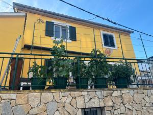 Una casa amarilla con plantas en macetas en un muro de piedra. en Bei Joschko, en Pakoštane