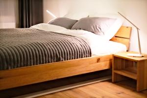 a bed with a wooden bed frame and a night stand at Aesten Mare Kühlungsborn Apartment 1 in Kühlungsborn +15 photos