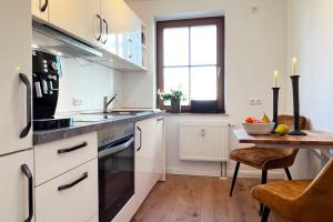 a kitchen with white cabinets and a table with a sink at Aesten Mare Kühlungsborn Apartment 1 in Kühlungsborn