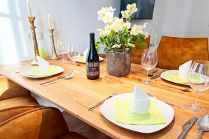 a wooden table with plates and glasses and a bottle of wine at Aesten Mare Kühlungsborn Apartment 1 in Kühlungsborn