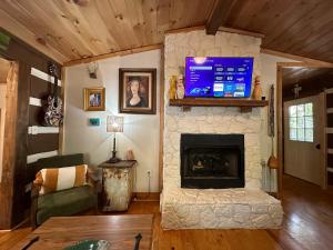 un soggiorno con camino e TV a schermo piatto di Eclectic Cabin - 5 Mins to DeSoto Park & Falls 