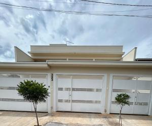 a house with white garage doors and two trees at Casa Tulipas in Holambra