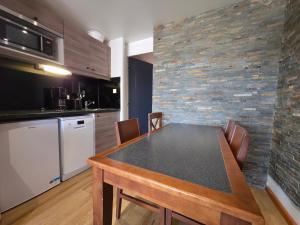 une cuisine avec une table avec des chaises et un mur en pierre dans l'établissement Studio central avec superbe vue sur les montagnes, à Huez 15 autres photos