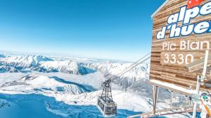 un panneau sur une remontée mécanique avec des montagnes enneigées dans l'établissement Studio central avec superbe vue sur les montagnes, à Huez