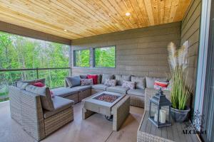 un portico riparato con divano e sedie di La Maison Eden Sauna & Spa Near Le Massif de Charlevoix a Petite-Rivière-Saint-François