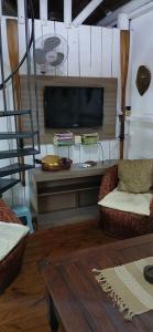 a living room with a flat screen tv and two chairs at Las chozas in Punta del Este