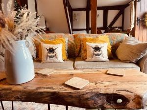 a couch with pillows on top of a wooden table at Log- burner, dog friendly- woodland views with walking trails and local pub on your doorstep! Popular walking trails nearby-Malvern Hills and the Brockhampton Estate- Peaceful village on the border of Hereford and Worcester in Worcester