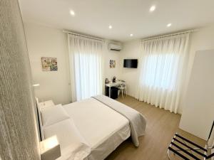 a bedroom with a white bed and a desk at B&B Il Tramonto in Capo dʼOrlando