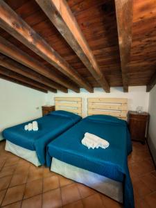 two beds with blue sheets in a room with wooden ceilings at Sebino Holiday Home Monteisola in Monte Isola
