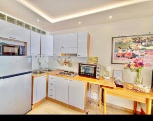 une cuisine avec des armoires blanches et une table avec un micro-ondes dans l'établissement Le Berkeley Bilocale fronte mare-Free Parking-Riscaldamento, à Menton