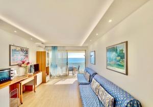 un salon avec un canapé bleu et une télévision dans l'établissement Le Berkeley Bilocale fronte mare-Free Parking-Riscaldamento, à Menton
