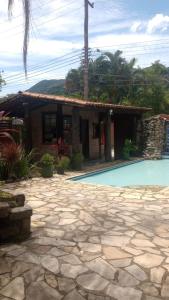 a house with a swimming pool in front of it at Catavento Flats e Suítes in Maresias +33 photos