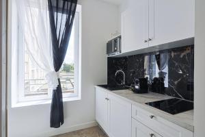Una cocina con gabinetes blancos y una ventana. en LES BULLES DE MONA - Lila - Spa - Clim, en Lyon