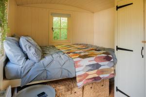 a small bedroom with a bed and a window at Hill Top Hideaway Shepherds Hut with Hot Tub in Purleigh