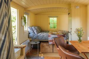 a tiny house with a couch and a table at Hill Top Hideaway Shepherds Hut with Hot Tub in Purleigh