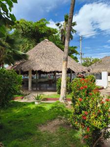 atropical building with a straw roof and some flowers at Las Margaritas Frente al Mar 1 in Coveñas