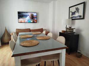 a dining room table with chairs and a tv on the wall at Apartamento Bidaya in Ronda