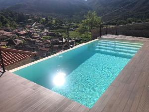 a large blue swimming pool with a view of a city at Casa Aurora in Campo do Gerês