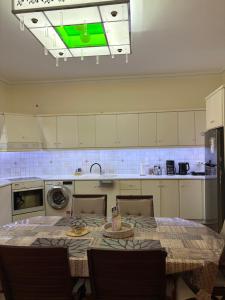 a kitchen with a table with chairs and a green light at HeidiHouse in Patra
