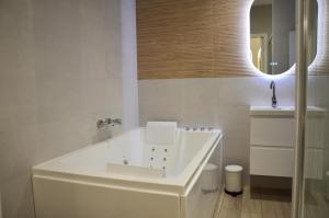 a white bathroom with a sink and a mirror at Suite cosy & centrale I Lit queen size I Balnéo in Aurillac +5 photos