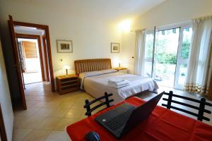 een slaapkamer met een bed en een laptop op een tafel bij casaisoladelba immersa nel verde a 80mt dalla spiaggia in Lacona