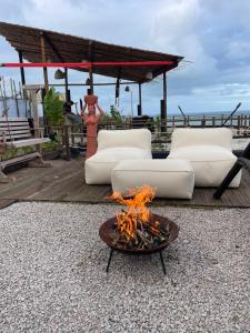 a fire pit with two white couches and a table at DChalé in Japaratinga