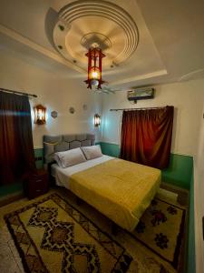 a bedroom with a bed and a chandelier at Raid rooftop atlas dades in Boumalne