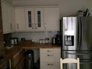 Una cocina con gabinetes blancos y un refrigerador de acero inoxidable. en Double ground floor room - Leicester free parking and drinks, en Leicester