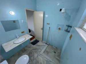 サルバドールにあるQuarto individual com suíte na Pitubaの青いバスルーム(洗面台、トイレ付)