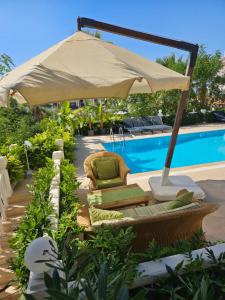 an umbrella and chairs next to a swimming pool at Villa Belle ,Fethiye in Fethiye