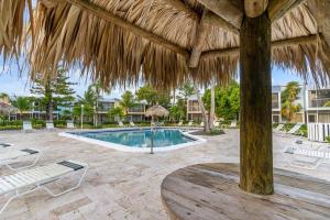 una piscina con ombrellone e sedie di paglia di New! Key Largo Costal Villa 2 Kings Masters, Marina, Pool & Pickleball a Key Largo