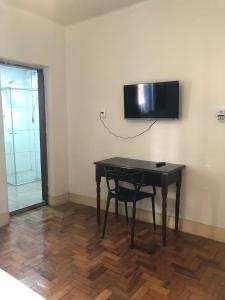 een tafel met een stoel en een televisie aan een muur bij Oxx in Congonhas