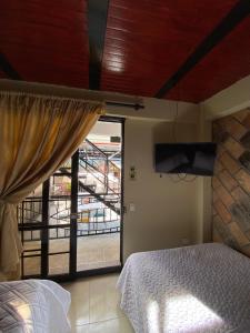 a bedroom with a bed and a tv and a window at HOTEL LA GAITANA HEROINA INDIGENA in San Agustín