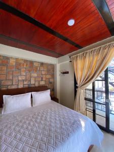 a bedroom with a bed and a brick wall at HOTEL LA GAITANA HEROINA INDIGENA in San Agustín