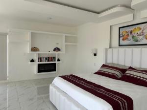 a white bedroom with a large bed and a fireplace at Mar de Calafia 1 in Divisadero